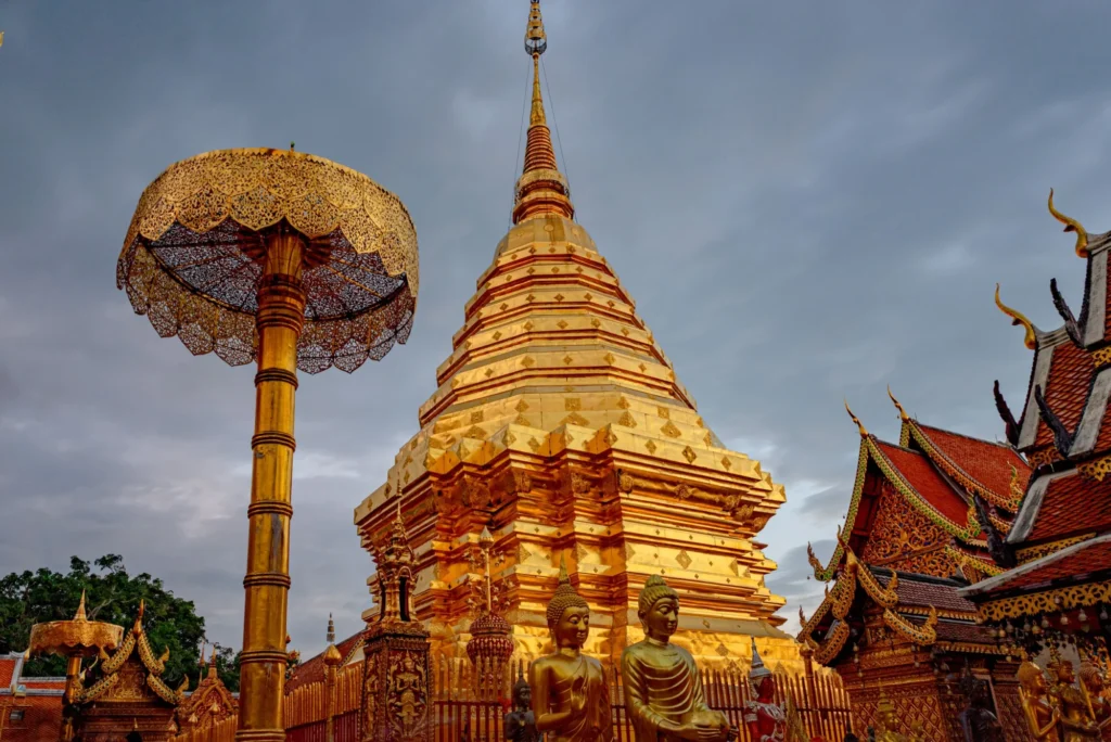Golden chedi and statues at Wat Phra That Doi Suthep under a cloudy sky