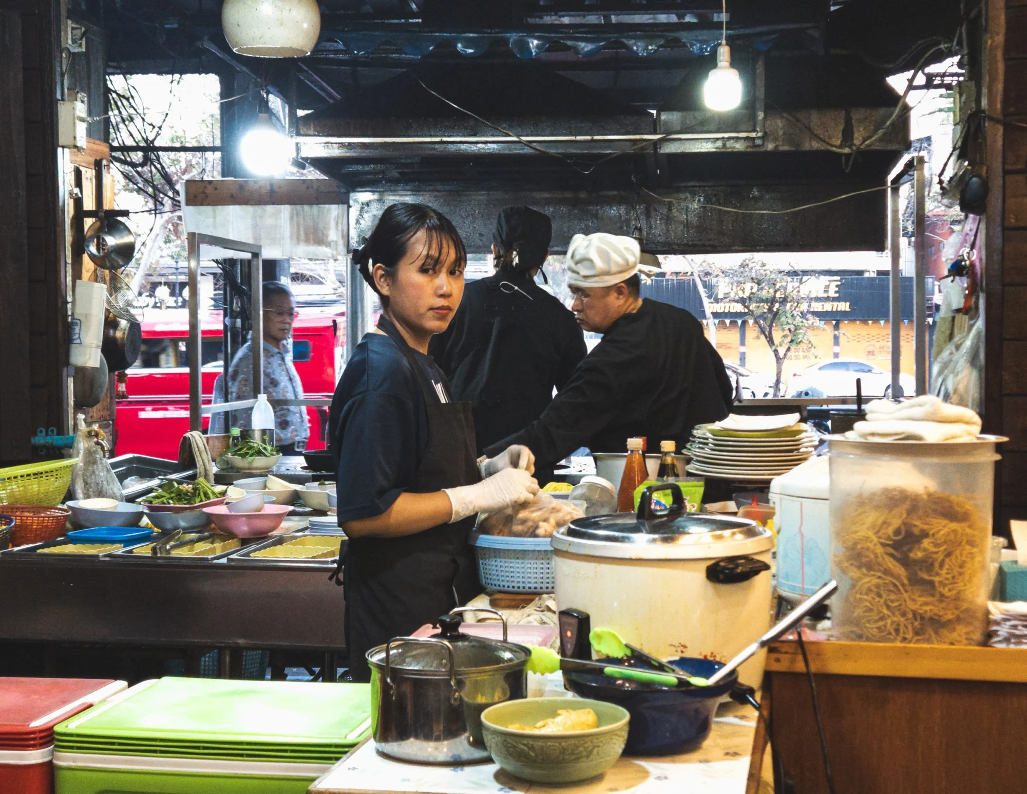 A food vendor preparing dishes behind the counter of a Chiang Mai food stall
