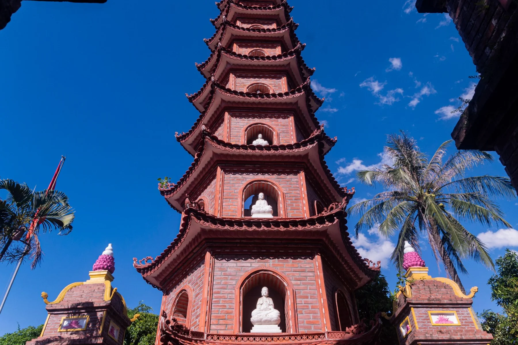 Red brick tower of Tran Quoc Pagoda against a blue sky in Hanoi