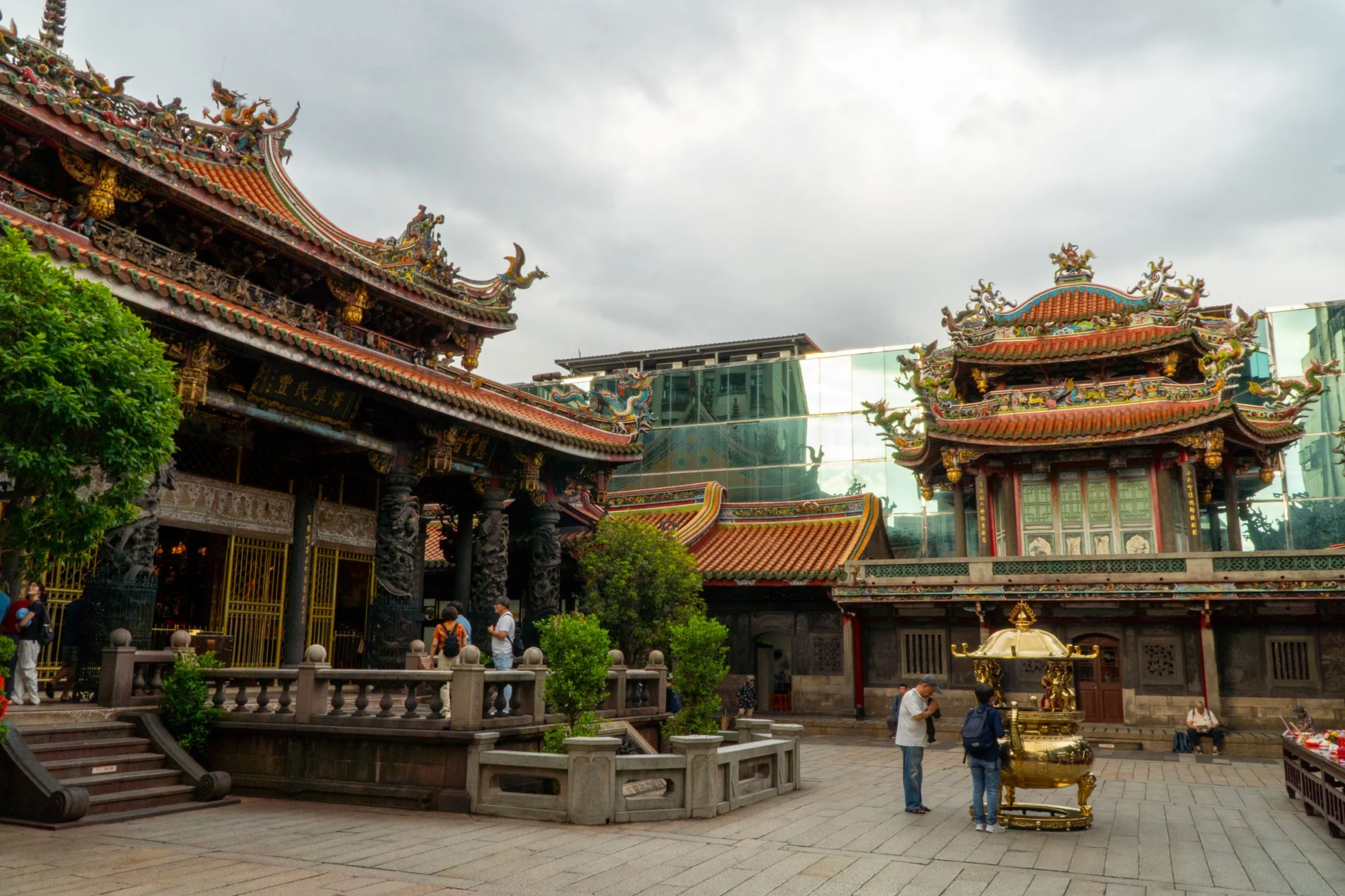 Ornate roofs and incense burner in the courtyard of Longshan Temple in Taipei