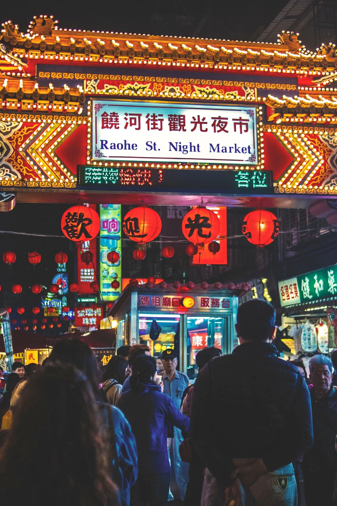 Illuminated entrance arch and visitors at Raohe Street Night Market in Taipei
